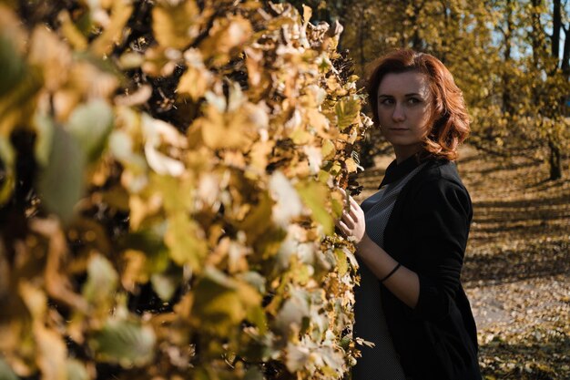 Vista laterale di una donna in piedi vicino alle piante durante l'autunno