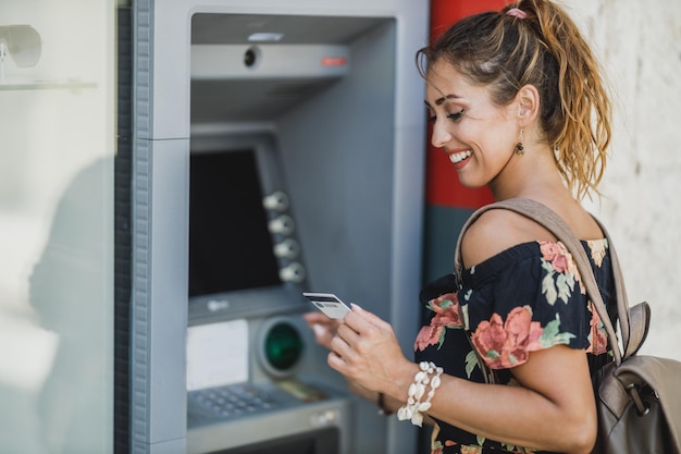 Vista laterale di una donna mentre preleva denaro dal bancomat.