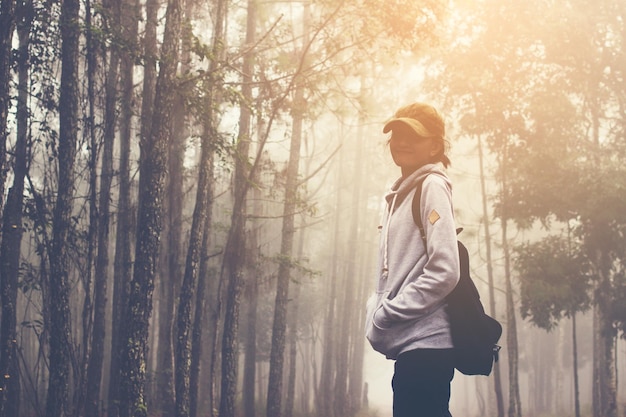 Vista laterale di una donna nella foresta durante il tempo nebbioso