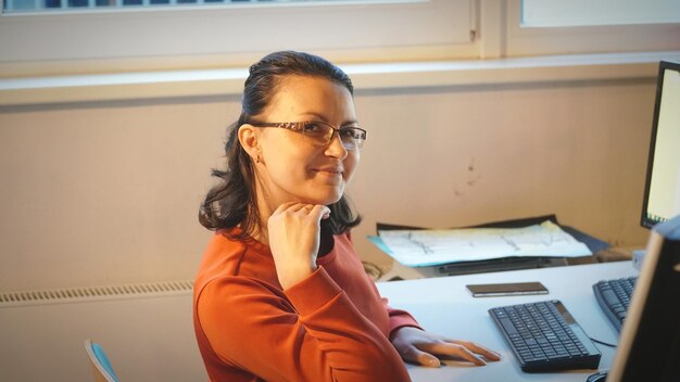 Vista laterale di una donna seduta a una scrivania in ufficio