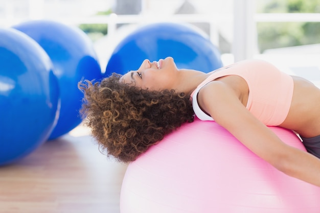 Vista laterale di una giovane donna adatta che si esercita sulla palla fitness