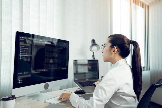 Vista laterale di una giovane donna che lavora al computer in ufficio
