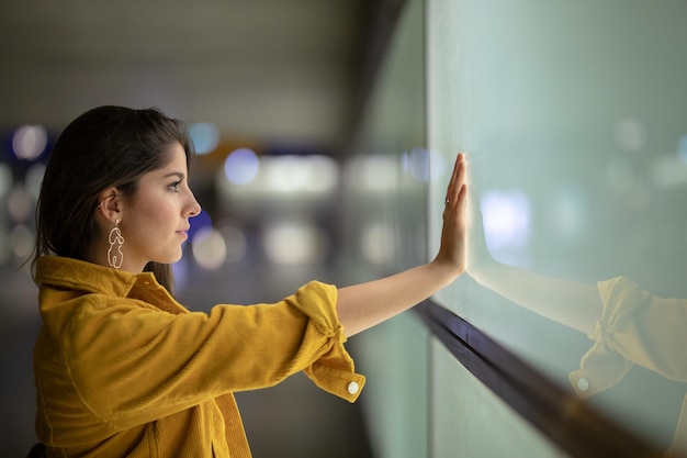 Vista laterale di una giovane donna che tocca la finestra