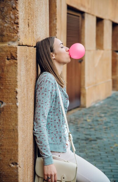 Vista laterale di una giovane donna con i palloncini in piedi contro l'edificio