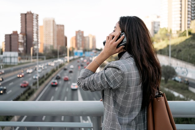 Vista laterale di una giovane donna d'affari che ha una conversazione al telefono È seria