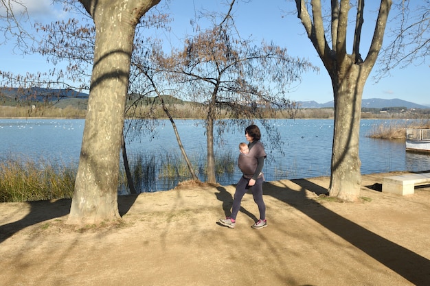 Vista laterale di una madre che si esercita portando fuori il figlio