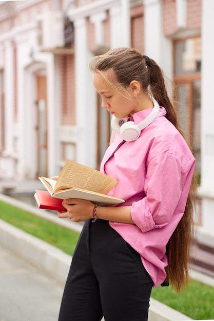 Vista laterale di una studentessa che legge un libro all'aperto