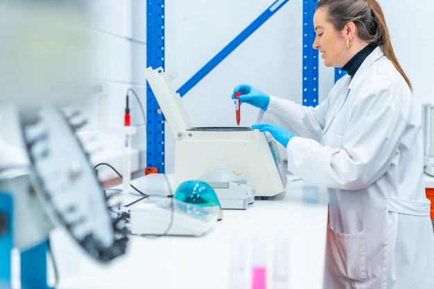 Vista laterale di uno scienziato sorridente che mette un campione di sangue in una centrifuga in un laboratorio di ricerca