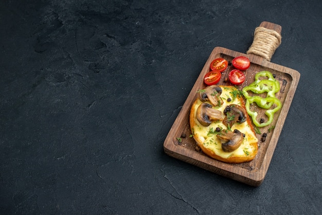 Vista laterale di uno spuntino gustoso fatto in casa con funghi e verdure tritate su tavola di legno su sfondo nero