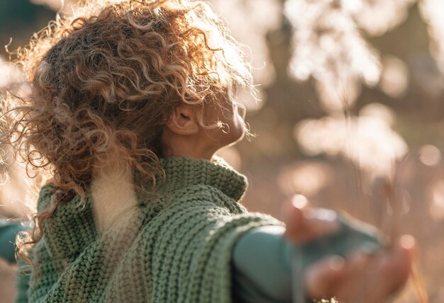 Vista laterale posteriore di una donna che gode della natura che stende le braccia e respira profondamente in un campo dorato con la luce del sole al tramonto Persone e attività di svago all'aperto Ambiente e libertà stile di vita sano