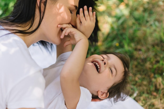 Vista laterale ritagliata della figlia del bambino felice e della madre che giocano all'aperto Mamma carina e il suo bambino che giocano insieme nel parco Ritratto del primo piano della famiglia felice Festa della mamma felice Maternità