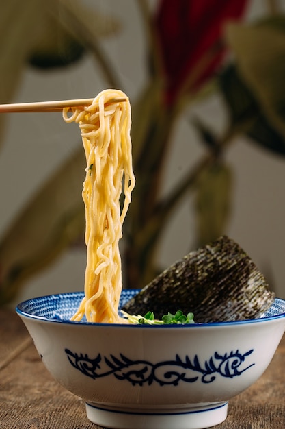 Vista laterale sul mangiare zuppa di spaghetti ramen giapponese con nori