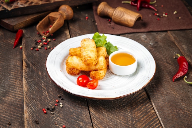 Vista laterale sulla mozzarella fritta con salsa sul tavolo di legno