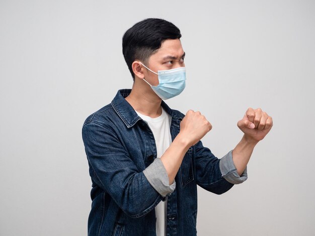 Vista laterale uomo jeans camicia indossare maschera medica gesto boxe per combattere con l'epidemia isolata