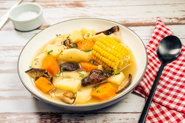 Vista macinata di una squisita zuppa di pollo, verdure e funghi fatta in casa con noodles e mais. Concetto di cibo naturale e sano