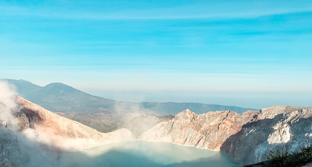 Vista mattutina della scogliera rocciosa del vulcano Kawah Ijen Crater con lago d'acqua di zolfo turchese