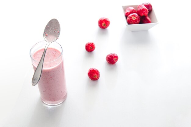 Vista minima del frullato di fragole e fragole su sfondo bianco piatto con spazio per la copia