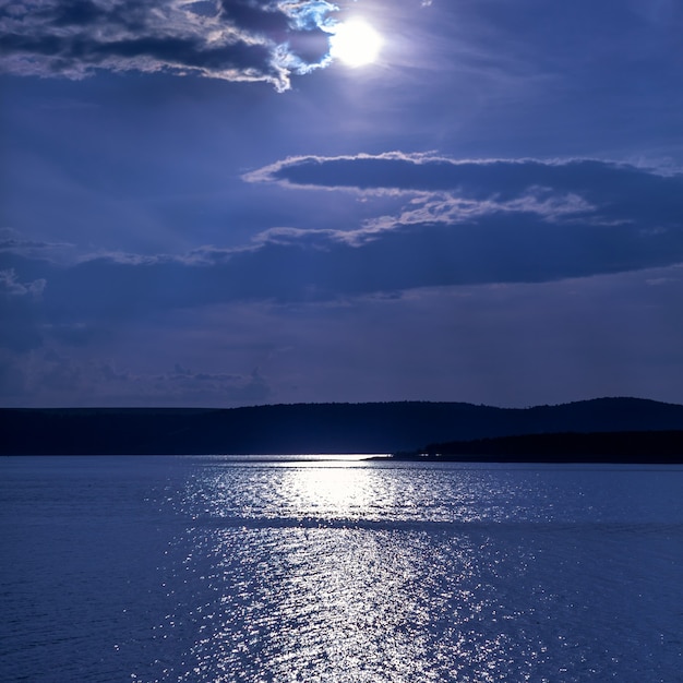 Vista notturna del lago, cielo con nuvole drammatiche e luna piena