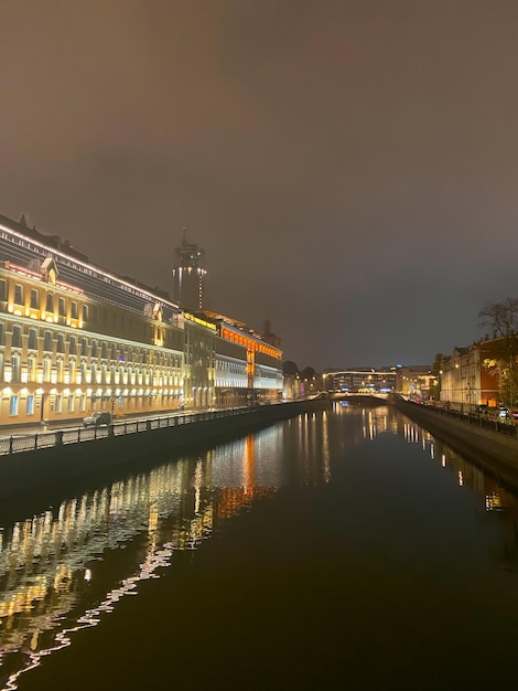 Vista notturna della città con messa a fuoco selettiva Le luci al neon della città si riflettono sul fiume di notte