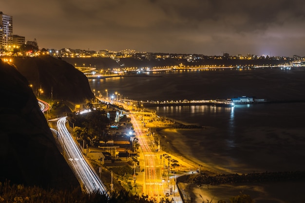 Vista notturna di automobili in un'autostrada vicino all'oceano