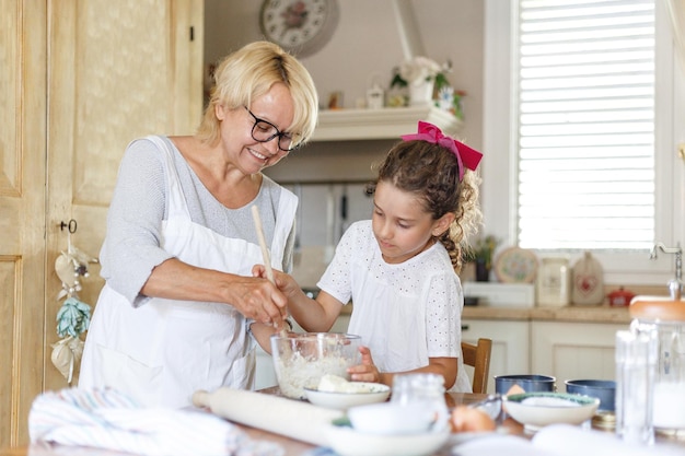 Vista orizzontale. Nonna e adorabile nipotina riccia in cucina, si stanno preparando insieme.