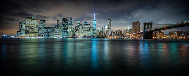 Vista panoramica del ponte di Brooklyn sul fiume da edifici illuminati al crepuscolo