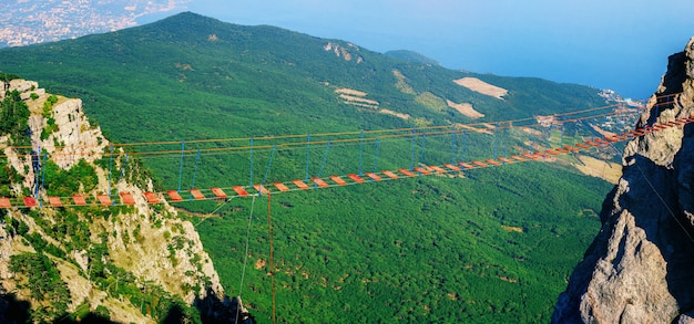 Vista panoramica del ponte di corda sospeso tra montagne rocciose o scogliere