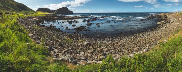 Vista panoramica della splendida costa della baia dell'Irlanda del Nord circondata da massi coperti di erba