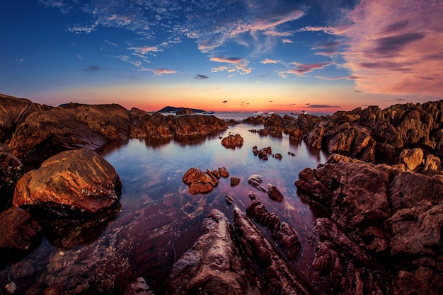Vista panoramica delle formazioni rocciose dal mare contro il cielo durante il tramonto