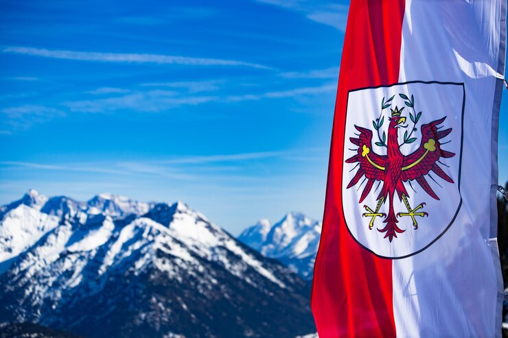 Foto vista panoramica delle montagne innevate contro il cielo blu con una bandiera austriaca