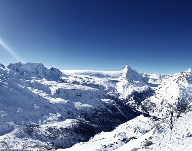 Vista panoramica delle montagne innevate contro un cielo blu limpido