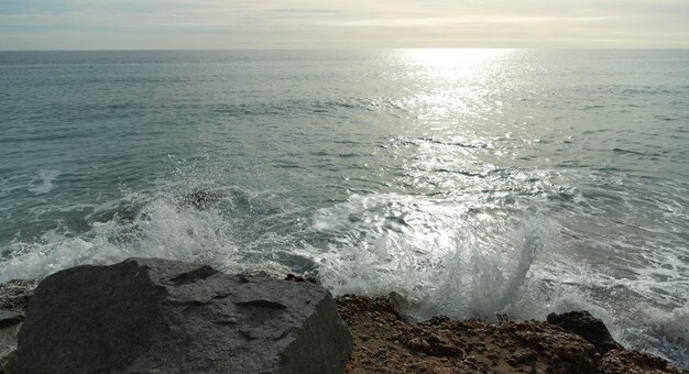 Vista panoramica delle onde che si infrangono sulle rocce in una baia al largo della costa della Spagna, Mar Mediterraneo