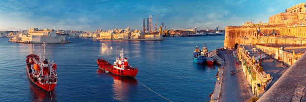 Vista panoramica dello skyline delle antiche difese di La Valletta e del Porto Grande con navi e tre città, tre città fortificate di Birgu, Senglea e Cospicua, all'alba. Malta.