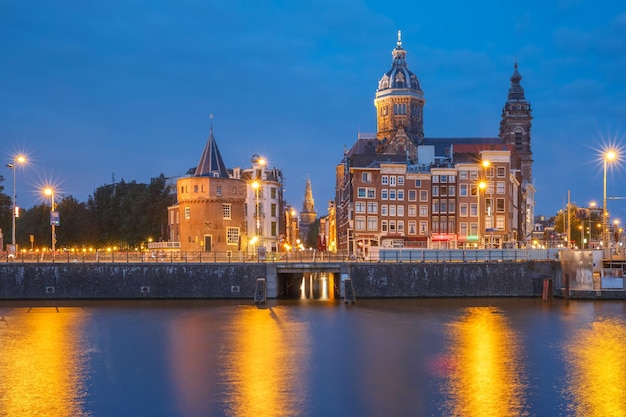 Vista panoramica notturna della città del ponte sul canale di amsterdam e della basilica di san nicola olanda netherlan...