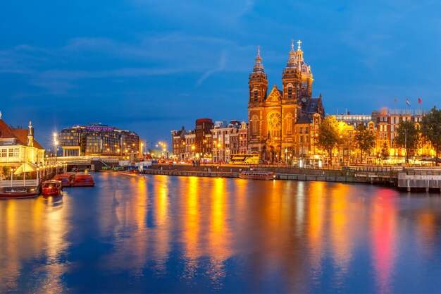 Vista panoramica notturna della città del ponte sul canale di amsterdam e della basilica di san nicola olanda netherlan