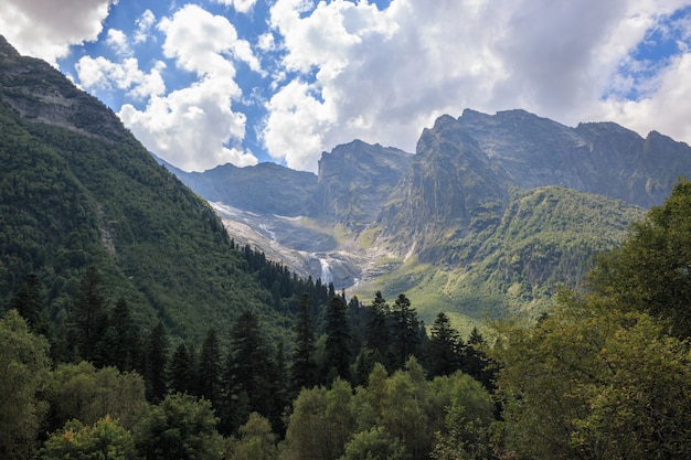 Vista panoramica sulla scena delle montagne e sulla cascata lontana nel parco nazionale di Dombay, Caucaso, Russia. Paesaggio estivo, tempo soleggiato e giornata di sole