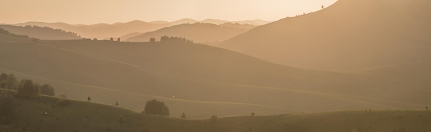 Vista panoramica sulle colline serali primaverili e sui pendii montuosi alla luce del tramonto