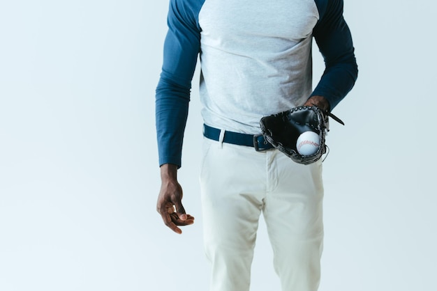 Vista parziale dello sportivo afroamericano con guanto da baseball e palla isolata su grigio