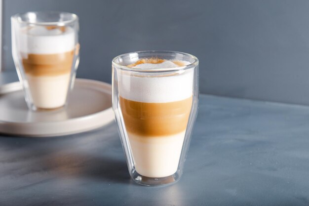 Vista perfettamente sfumata del latte macchiato su uno sfondo grigio con spazio per la copia