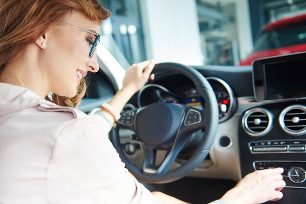 Vista posteriore dei capelli biondi di una donna che prova una nuova auto