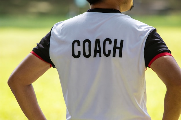 Vista posteriore del calcio maschile o allenatore di calcio in camicia bianca con scritta COACH scritta sul retro