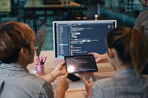 Vista posteriore del codice di programmazione del team di sviluppatori IT sullo schermo del computer e brainstorming per un nuovo progetto in un ufficio moderno