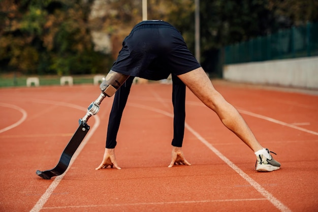 Vista posteriore del corridore disabile in posizione di partenza per la corsa allo stadio sulla pista da corsa