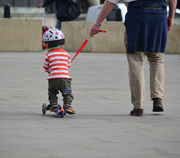 Vista posteriore del figlio in piedi su uno scooter push con il padre in strada