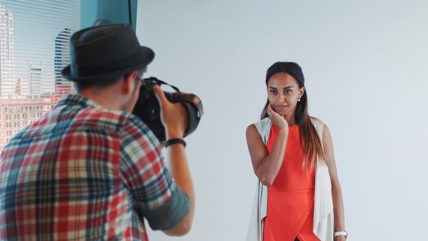 Vista posteriore del fotografo che scatta foto della bellissima modella multirazziale in studio che posa in fr...