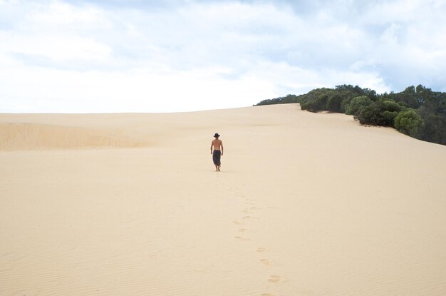 Vista posteriore del giovane che cammina su una duna di sabbia in uno spazio di copia del concetto di DayExploration Sunny DayExploration