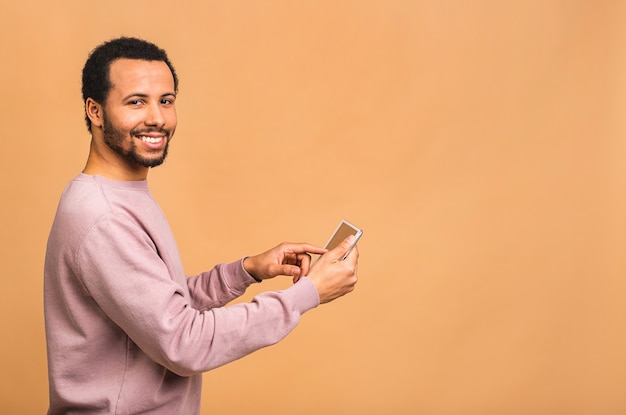 Vista posteriore del giovane uomo che lavora sulla tavoletta digitale mentre in piedi isolato su beige.