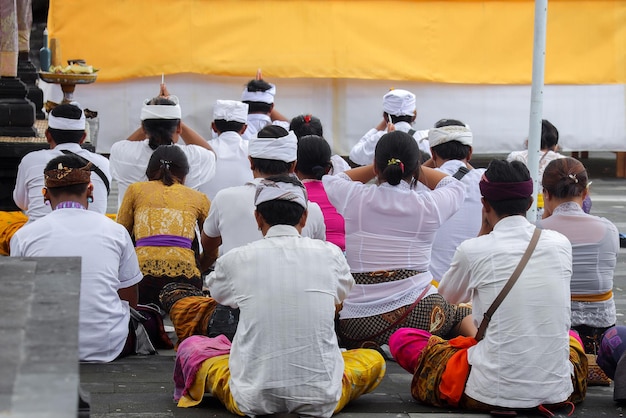 Vista posteriore del popolo balinese con abiti tradizionali che pregano insieme