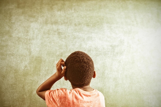 Vista posteriore del ragazzo premuroso contro greenboard