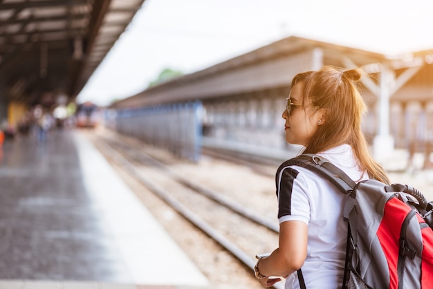 Vista posteriore del treno aspettante turistico della giovane donna asiatica alla stazione ferroviaria